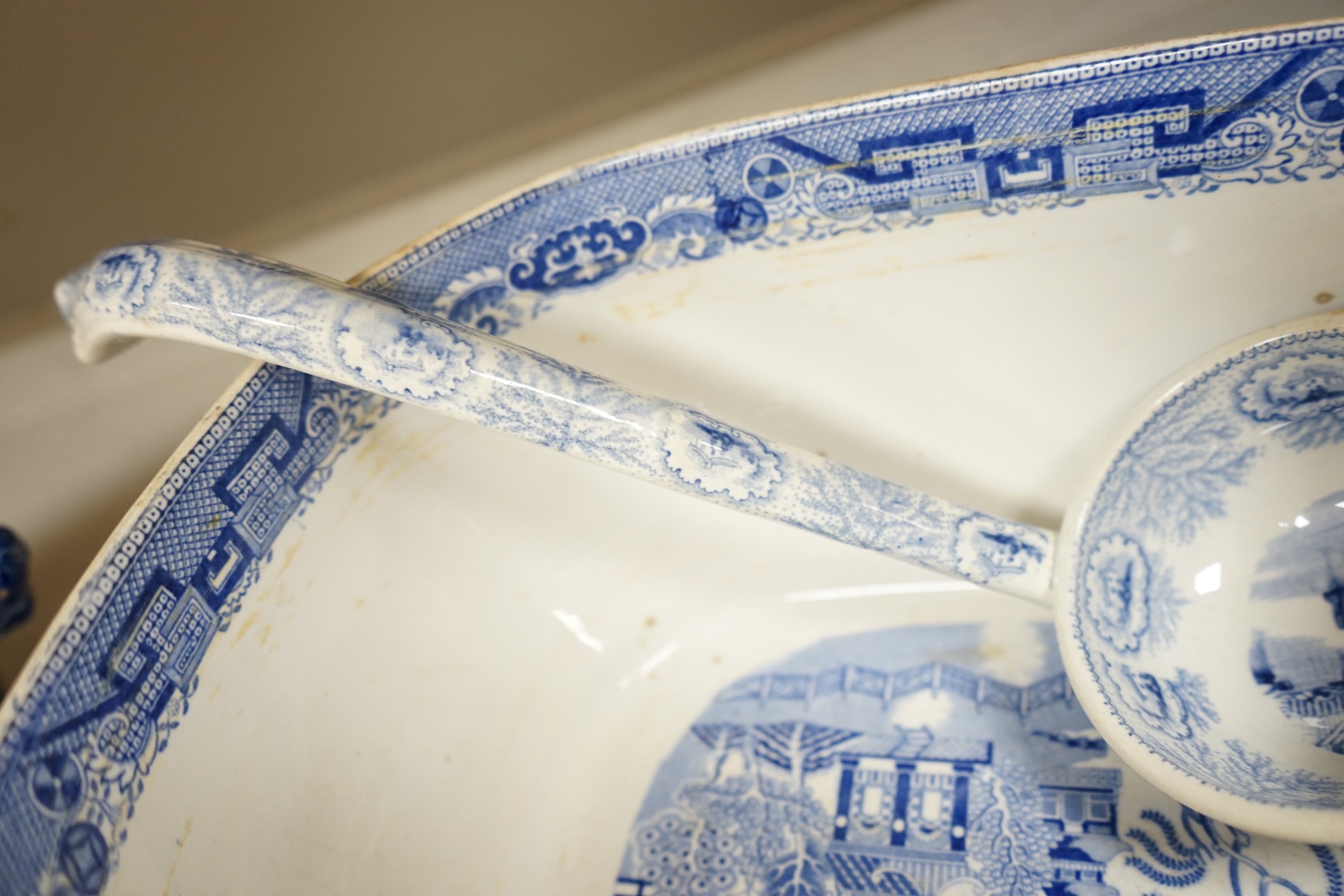 A large early to mid 19th century Pearlware meat platter and tureen without cover decorated with the ‘doctor calling’ pattern with a blue and white tureen cover and ladle, meat platter 54cm wide (3). Condition - fair